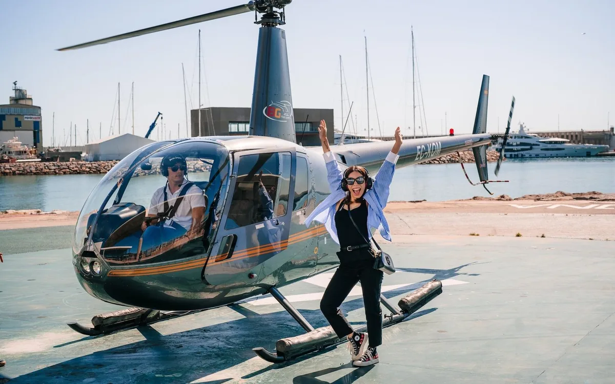 A passenger beside a helicopter on the apron at Barcelona Heliport
