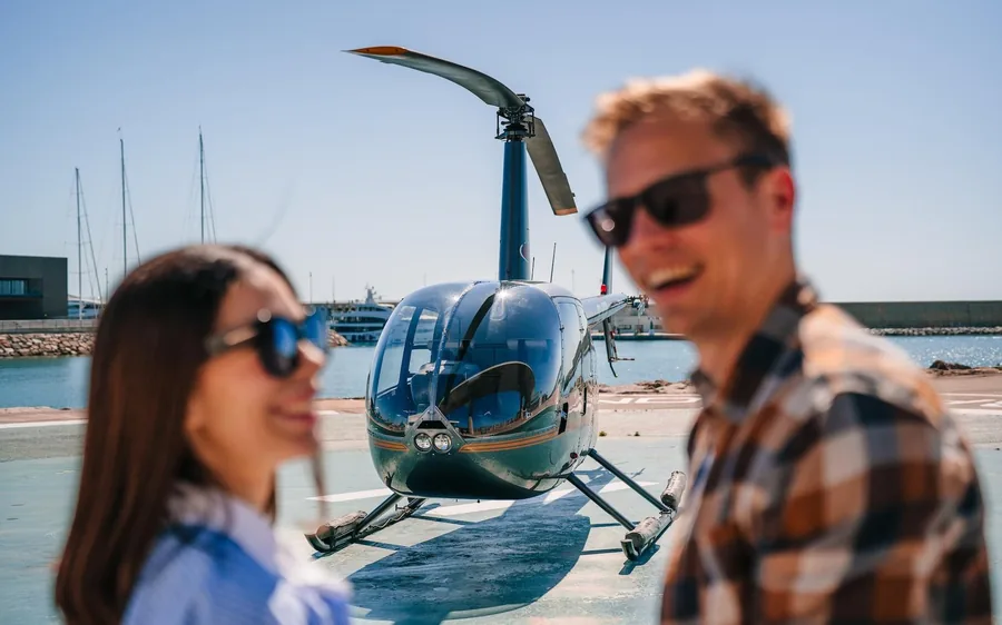 Two passengers beside a helicopter at the Barcelona waterfront